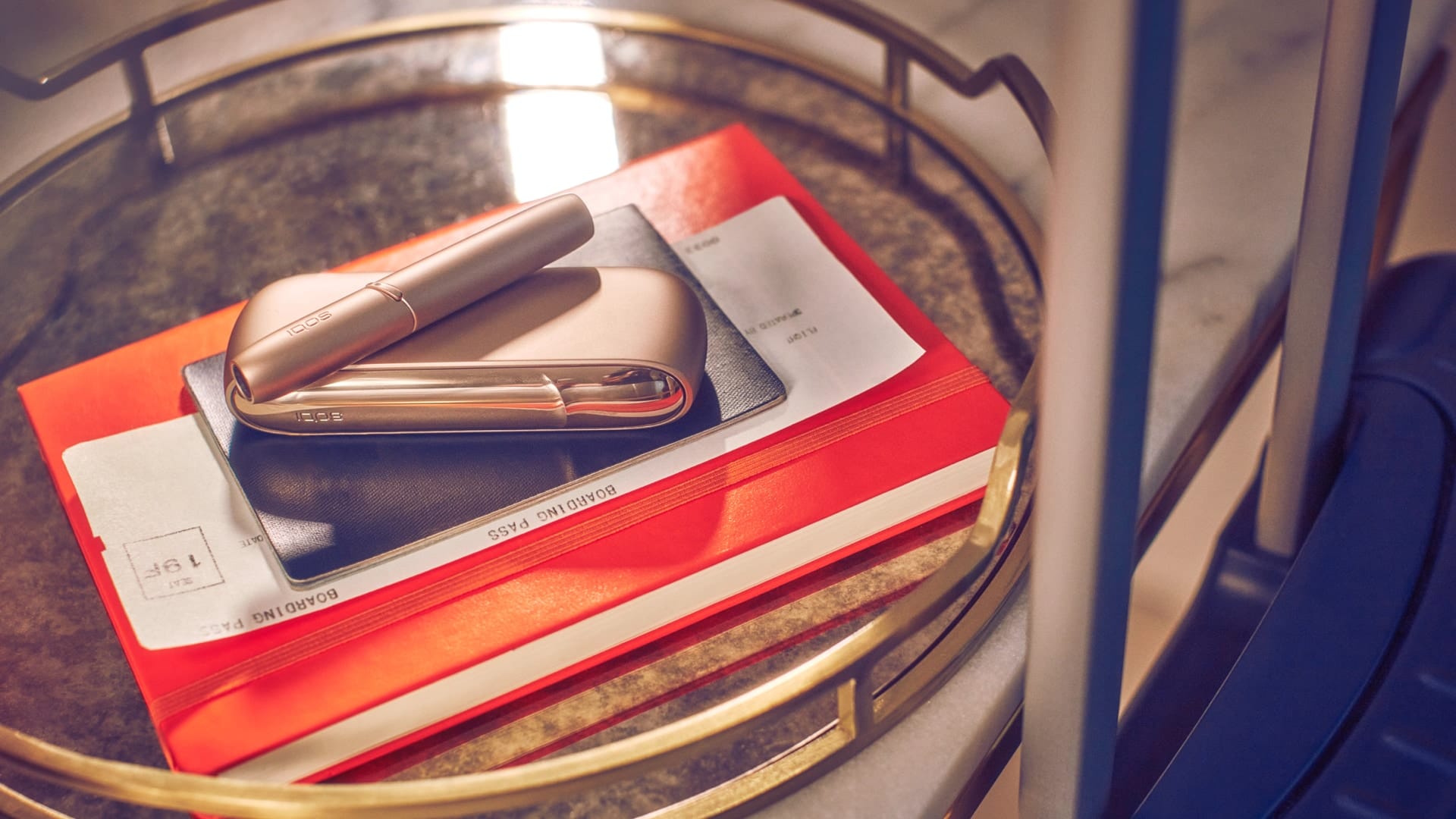 A gold IQOS DUO device on an orange copybook