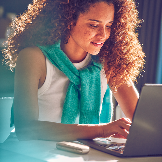 Woman infront of laptop with IQOS 3 DUO gold kit beside