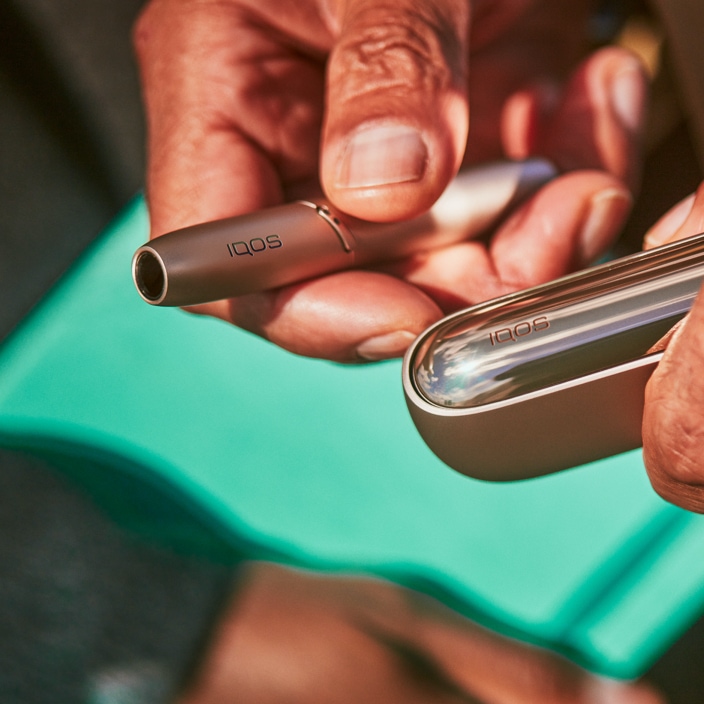 White IQOS 3 DUO holder and charger on a picnic table