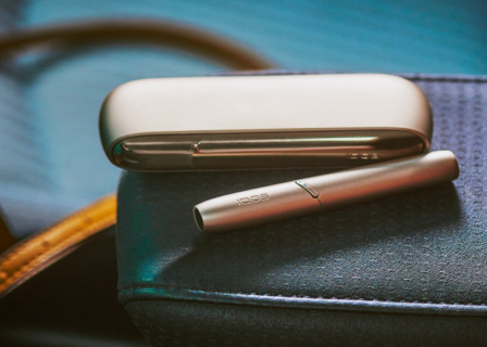 Stellar blue IQOS 3 Duo holder and charger with HEETS stick on a table next to popcorn