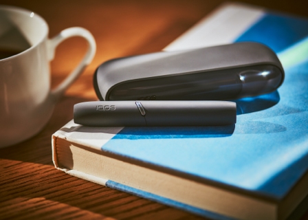 Black IQOS 3 DUO holder with HEETS stick and charger on a book