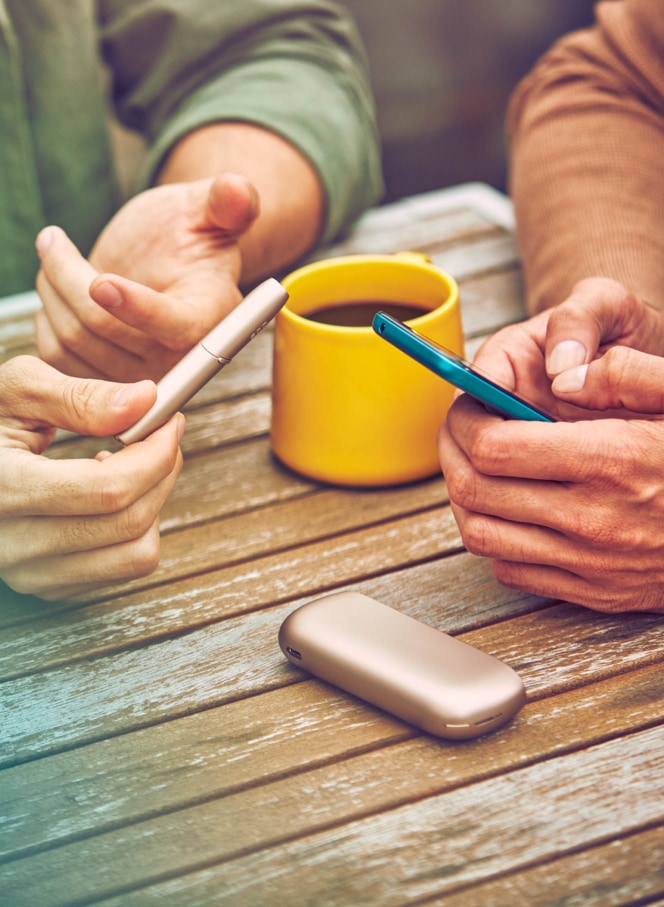 Man with a gold IQOS Duo and a mobile in his hands