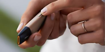 Man with a gold IQOS Duo and a mobile in his hands