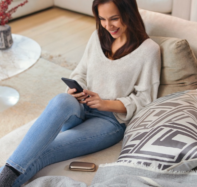 A woman reclines on a day bed while looking at her mobile phone.